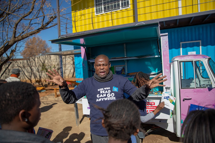 Dumezweni Nkala speaks to children about Nal’ibali’s new mobile tuk-tuk outside the Ikageng Library in Orlando West, Soweto.