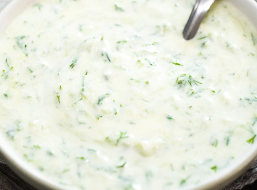 Tzatziki sauce in bowl with spoon