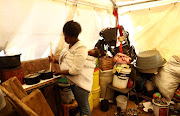 Nhlanhla Mabuza's little corner in the subdivided tent is crammed with buckets, stacked boxes, basins for washing, containers for water, a mattress and makeshift beds. Her cooking is done on a paraffin stove. 