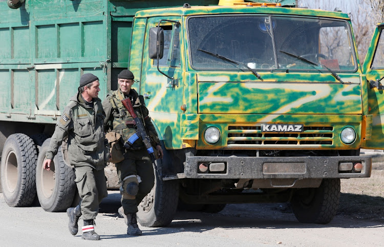 Service members of pro-Russian troops walk along a road during Ukraine-Russia conflict on a road near the besieged southern port city of Mariupol, Ukraine March 21, 2022.