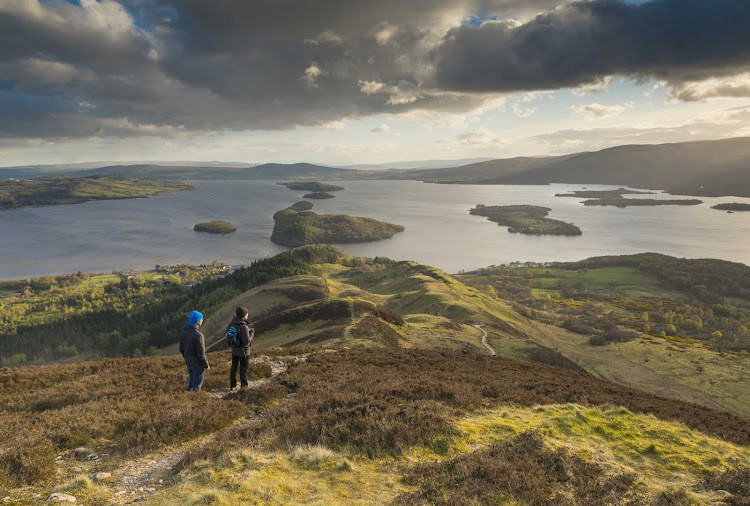 Hikers take in Loch Lomond from Conic Hill, part of the West Highland Way in the Loch Lomond region of Scotland. 