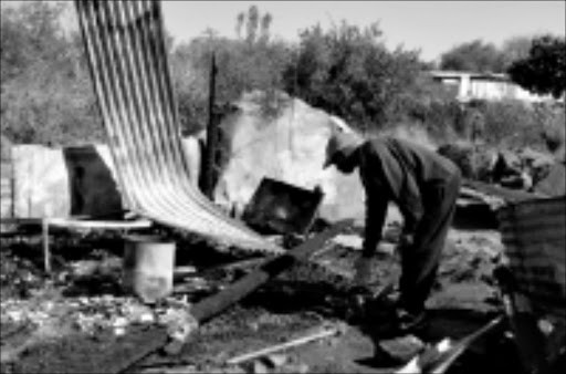 SAD REMINDER: A member of the family looks at the remains of the shack that burnt down, in which five members of a family died. The tragedy occurred at Temba in Hammanskraal, outside Pretoria, on Sunday night. Pic. Munyadziwa Nemutudi. 28/07/08. © Sowetan.