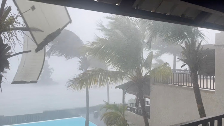 Part of the roof flies off a building as Cyclone Freddy batters Trou-aux-Biches, Mauritius, February 20 2023 in this still image obtained from social media video.