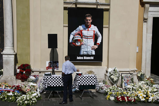 A man pays his respects below a poster showing late French Formula One driver Jules Bianchi, after the funeral ceremony for Bianchi at the Cathedrale Sainte Reparate in Nice on July 21, 2015, southeastern France. Nine months after his horror crash during the Japan Grand Prix in Suzuka, Bianchi died on July 17, 2015 in a hospital of his hometown of Nice from head injuries sustained in the October 5 accident. AFP PHOTO / VALERY HACHE