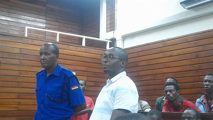 Taita Tavea Deputy Speaker Anselm Mwadime standing next to a police officers after he was arraigned before a Mombasa Magistrate Court on Monday.