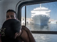 vrouw omarmd man en kijkt uit raam naar cruiseschip