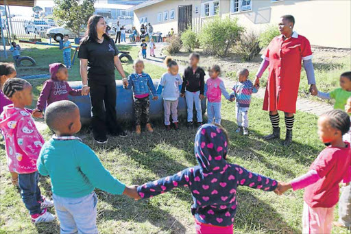 HAND-IN-HAND: Salem Baby Care Centre director Lereen Naidoo, left, and helper Xoliswa Cungwa play with some of the little ones who attend the centre’s creche Picture: MICHAEL PINYANA