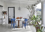 The dining area on the farmhouse's verandah offers a sheltered outdoor option for dining. The furniture is a mix-and-match of hand-me-downs.