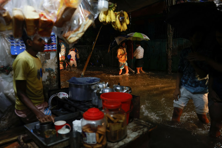 People wade through a flooded street, amid continuous rain before the Cyclone Sitrang hits the country in Dhaka, Bangladesh, October 24, 2022.