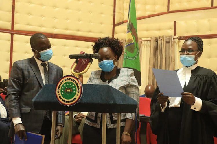 Eng Rosalia Lumonya Soita Masinde (Water). Is helped to take oath as legal advisor Cryil Wanyongo and lawyer Annte Mumalasi watch over