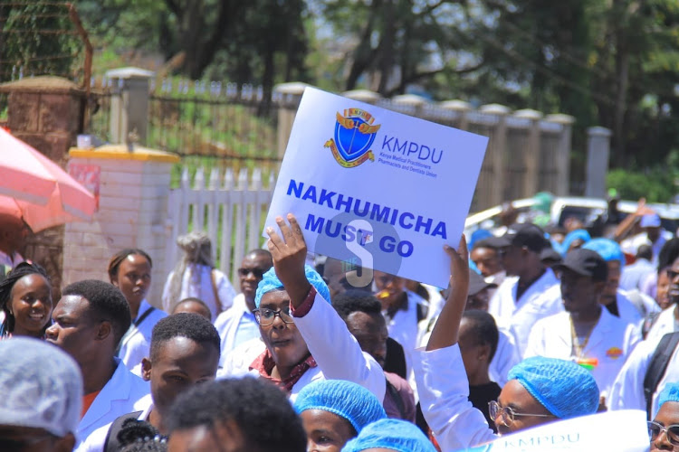 A doctor holds a placard as they protest along Ngong road to ministry of Health over the posting of interns on March 22, 2024.