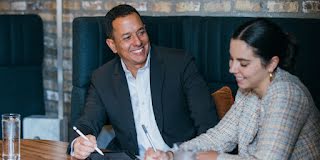 Man in Blazer Holding a Pen and looking at lady.