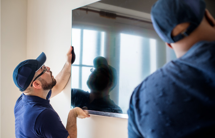 Professional movers taking a TV off of a wall during a residential move.