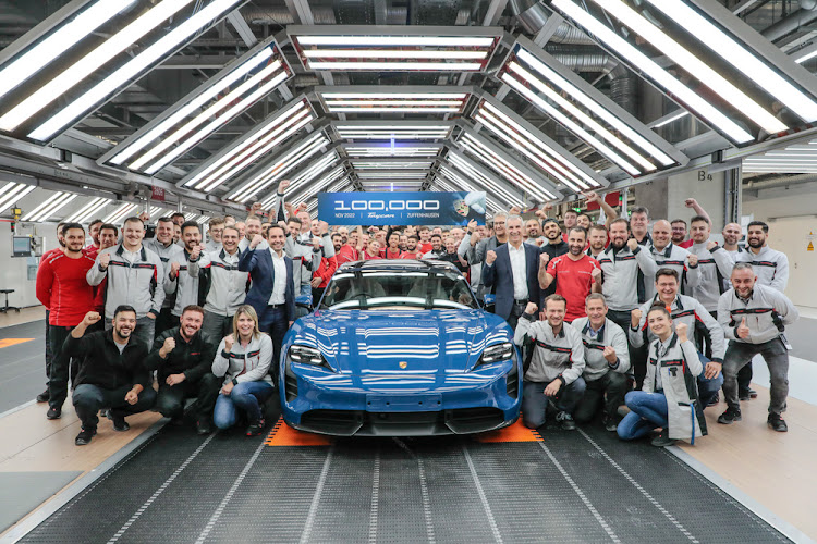 Porsche staff pose with the 100,000th Porsche Taycan at its assembly plant.