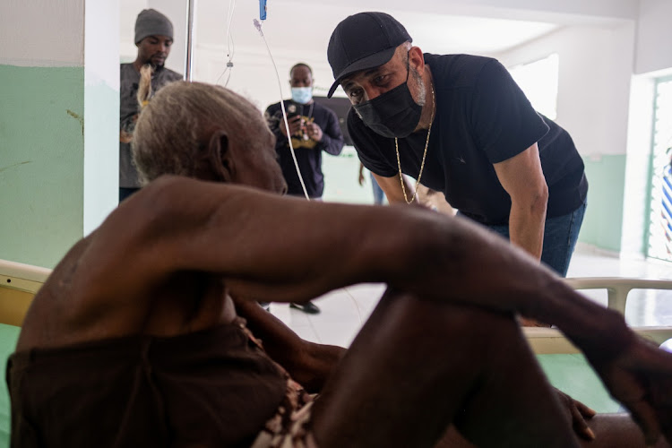 Former Haitian President Michel Martelly speaks to a woman injured during the 7.2 magnitude quake at the OFATMA hospital in Les Cayes, Haiti on August 20, 2021.