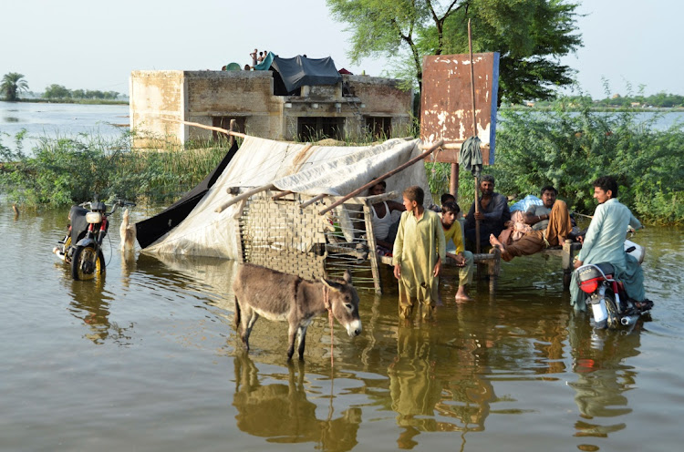 People are seen outside their flooded house after rains and floods during the monsoon season in Suhbatpur, Pakistan, on August 28.