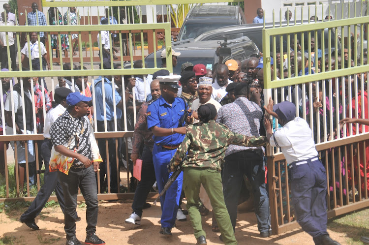 Former Nairobi governor Mike Sonko (in blue cap) makes his way at the Kenya School of Government, Mombasa, as police block the gate on Tuesday, June 6, 2022.