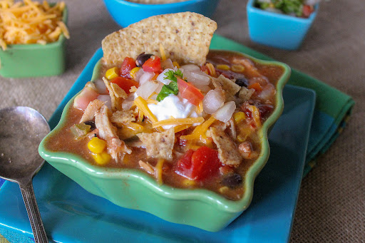 Kickin' Chicken Taco Soup topped with shredded cheddar cheese, sour cream, and pico de gallo.