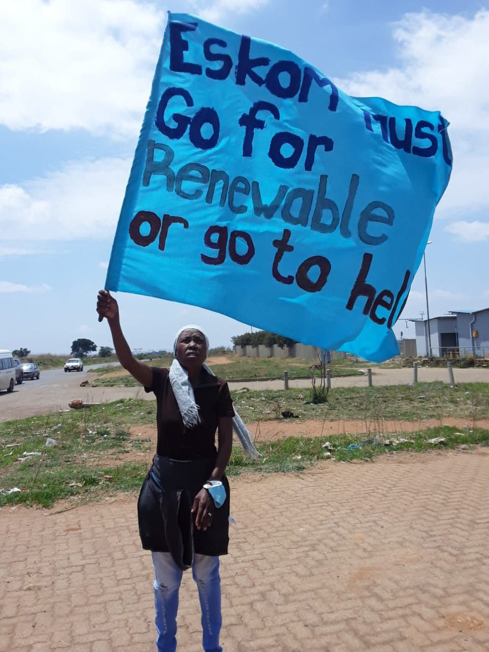 A rebel holds up a huge flag that says Eskom must go for renewable or go to hell.