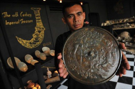 A man holds a 10th century Chinese bronze mirror plate from the Five Dynasties (907-960) at a showroom in south Jakarta. File picture