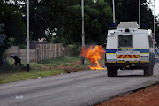A protester takes cover after throwing a petrol bomb at a Police Nyala  riot vehicle. File photo.