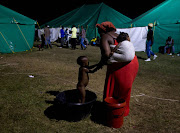 A woman bathes her son in a plastic basin in Isipingo, south of Durban. Several hundred foreign nationals have sought refuge in the tents after xenophobia driven violence forced them to flee their homes and businesses. REUTERS