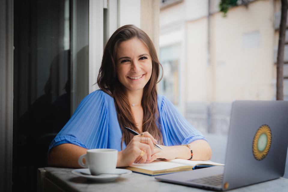 attractive woman working on a laptop and drinking coffee in italy in a coworking space