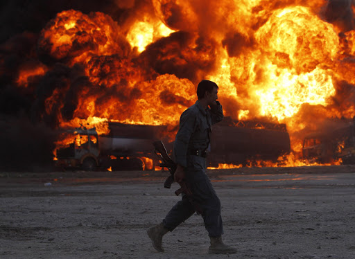 An Afghan policeman runs in front of a tanker on fire in Kabul.