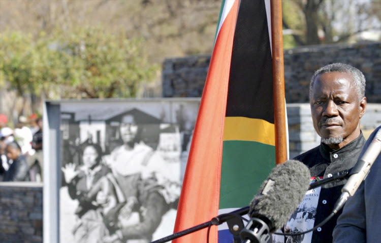 Sam Nzima poses next to his famous picture of Hector Pieterson