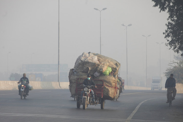 FILE PHOTO: A man rides a motor tricycle, loaded with sacks of recyclables, amid dense smog in Lahore, Pakistan November 24, 2021. Picture: MOHSIN RAZA/REUTERS/FILE PHOTO