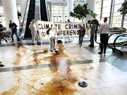 Extinction Rebellion activists spread pools of oil in the entrance to Africa Oil Week at Cape Town International Convention Centre on November 5 2019.