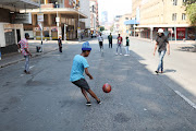 Residents play soccer in the street, 20 March 2023, in Braamfontein, Johannesburg CBD. Due to threats from the national shutdown many businesses have closed their doors for the day. 