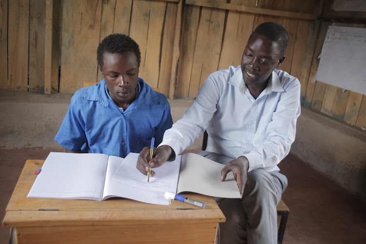 Kapkomoi Secondary school principal Nicholas Choge (right) teaches the only Form 1 student on Thursday.