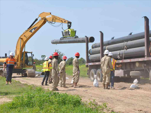 A crane loads pipes onto a truck to be used in the construction of Mombasa – Nairobi oil pipeline. /FILE