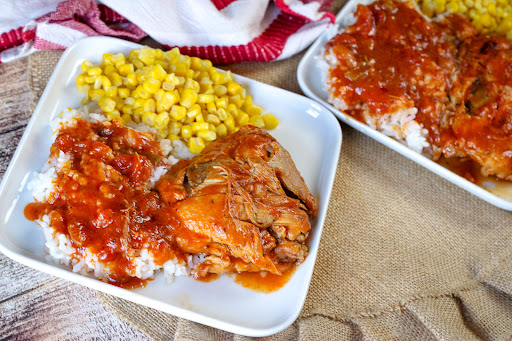 Chicken and Tomato Gravy over rice on a plate.