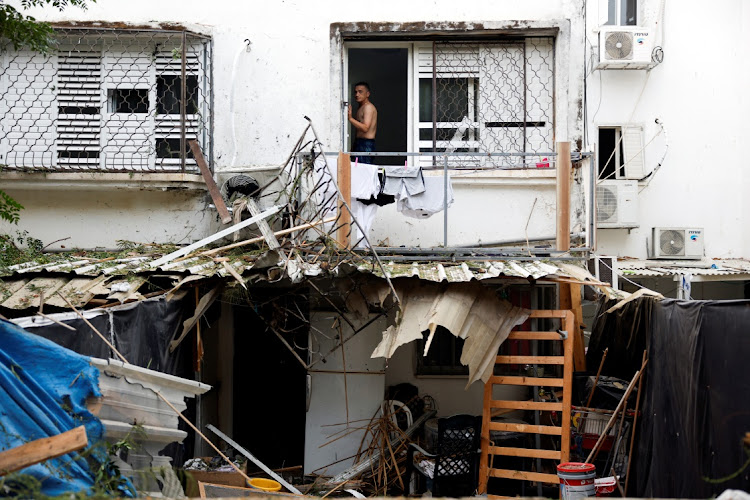 An Israeli man looks out from a window of a building that was hit following rockets from Gaza that were launched towards Israel in Ashkelon, southern Israel, on October 9. Picture: REUTERS/AMIR COHEN