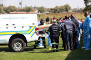 Forensic pathologists load five-year-old Nqobizitha Zulu's mutilated body into the back of their van. 