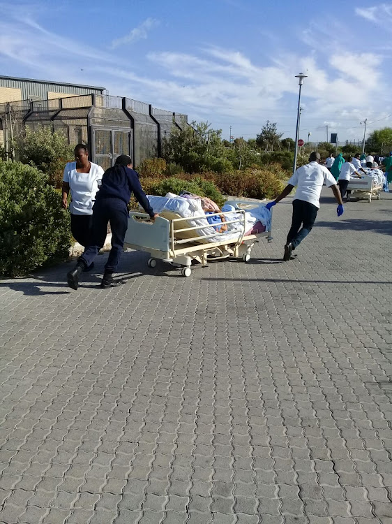 Patients and staff evacuate Mitchells Plan District Hospital in Cape Town early on Saturday after fire broke out in the roof void.