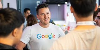 Man wearing a Google tshirt talking to a group of people.