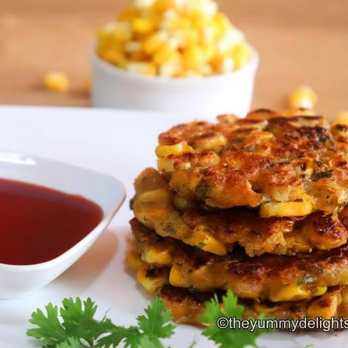 image of crispy fritter served with tomato sauce. Garnished with coriander leaf & fresh corn kernels in the background.