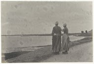 Twee vrouwen in Volendamse klederdracht staand op een dijk