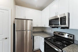 Kitchen with white shaker cabinets, stainless steel appliances, gray speckled granite countertops and brushed nickel hardware