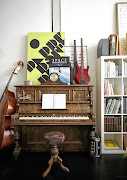 Two bass guitars, one made by the homeowner's father, sit on top of an inherited piano.