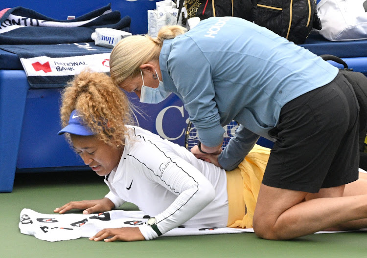 Japan's Naomi Osaka is treated for a back injury before withdrawing from her match against Kaia Kanepi of Estonia at Sobey's Stadium Centre, North York, Ontario on August 9, 2022