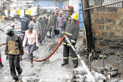 HORROR: People watch as rescuers work at the scene of the fire at a slum in Nairobi. More than 100 people are said to have burnt to death and a similar number were taken to hospital. photo: REUTERS