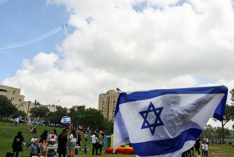 A man celebrates with Israeli flags as Israeli Air Force planes fly in formation over Jerusalem an aerial show as part of the celebrations for Israel's Independence Day, marking the 74th anniversary of the creation of the state, at Sacher Park in Jerusalem May 5 2022. Picture: REUTERS/RONEN ZVULUN