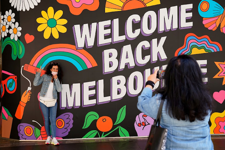 People take photos in front of a 'Welcome Back' sign in Melbourne after coronavirus disease (Covid-19) restrictions were eased for the state of Victoria, Australia.