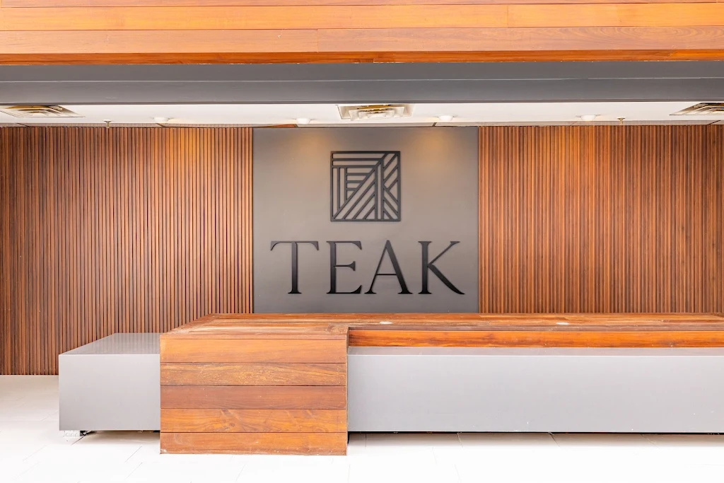 Teak living leasing office desk made of wood and stone with wooden accent wall behind