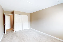 Bedroom with plush carpet and light brown walls with a double door closet