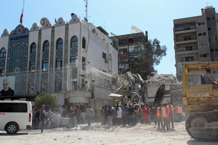 Civil defence members and workers clear rubble after a suspected Israeli strike on Monday on Iran's consulate, adjacent to the main Iranian embassy building, which Iran said had killed seven military personnel including two key figures in the Quds Force, in the Syrian capital Damascus, Syria April 2, 2024.